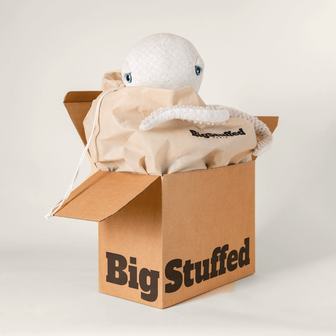 The Giant Octopus peeking out of a BigStuffed gift box with kraft wrapping paper