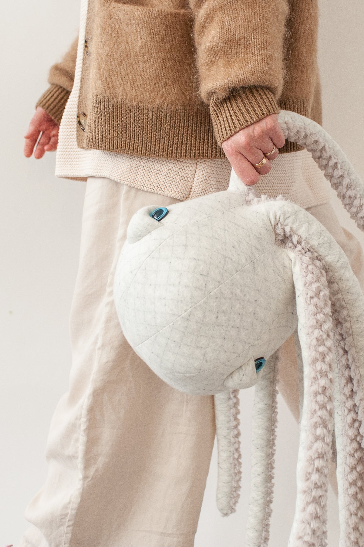 Carrying a giant cream octopus plush by one of its long arms