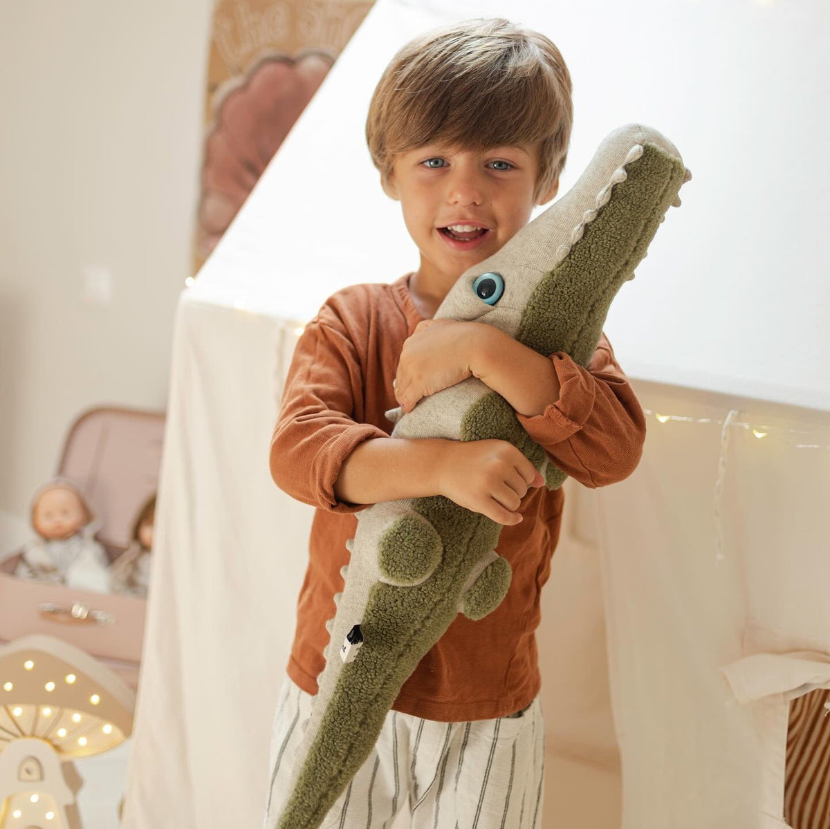 Smiling boy hugging a big green crocodile plush